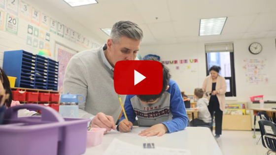 Principal sitting at table helping student