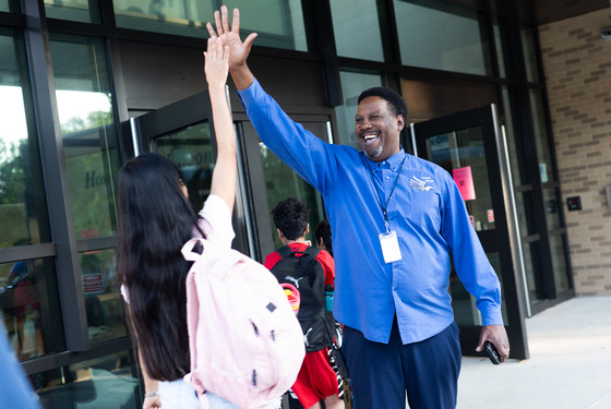 An adult high fives a middle school student