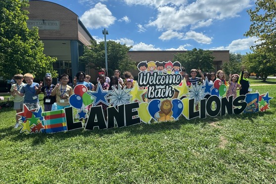 Second graders standing behind a big Welcome Back to School, Lane Lions! sign