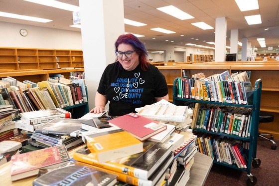 a person looks at a pile of library books on a table