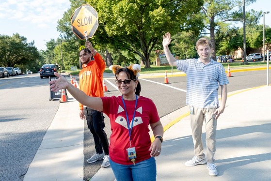 employees wave to new students on the first day