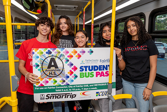 Three students hold giant Student Bus Pass