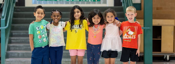 Group of students standing side by side with their arms around one another