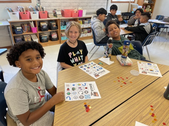 Students sitting a table with Technology BINGO games. 