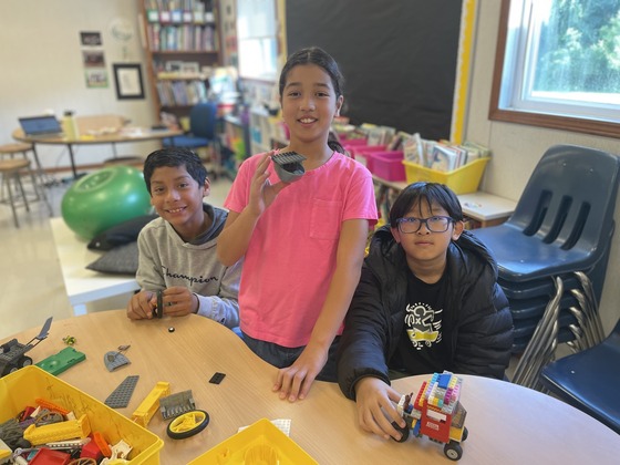 Three students use legos to build in the classroom