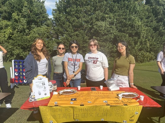 Students standing on one side of the table, outside.