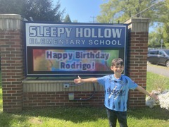 student in front of birthday message on digital sign