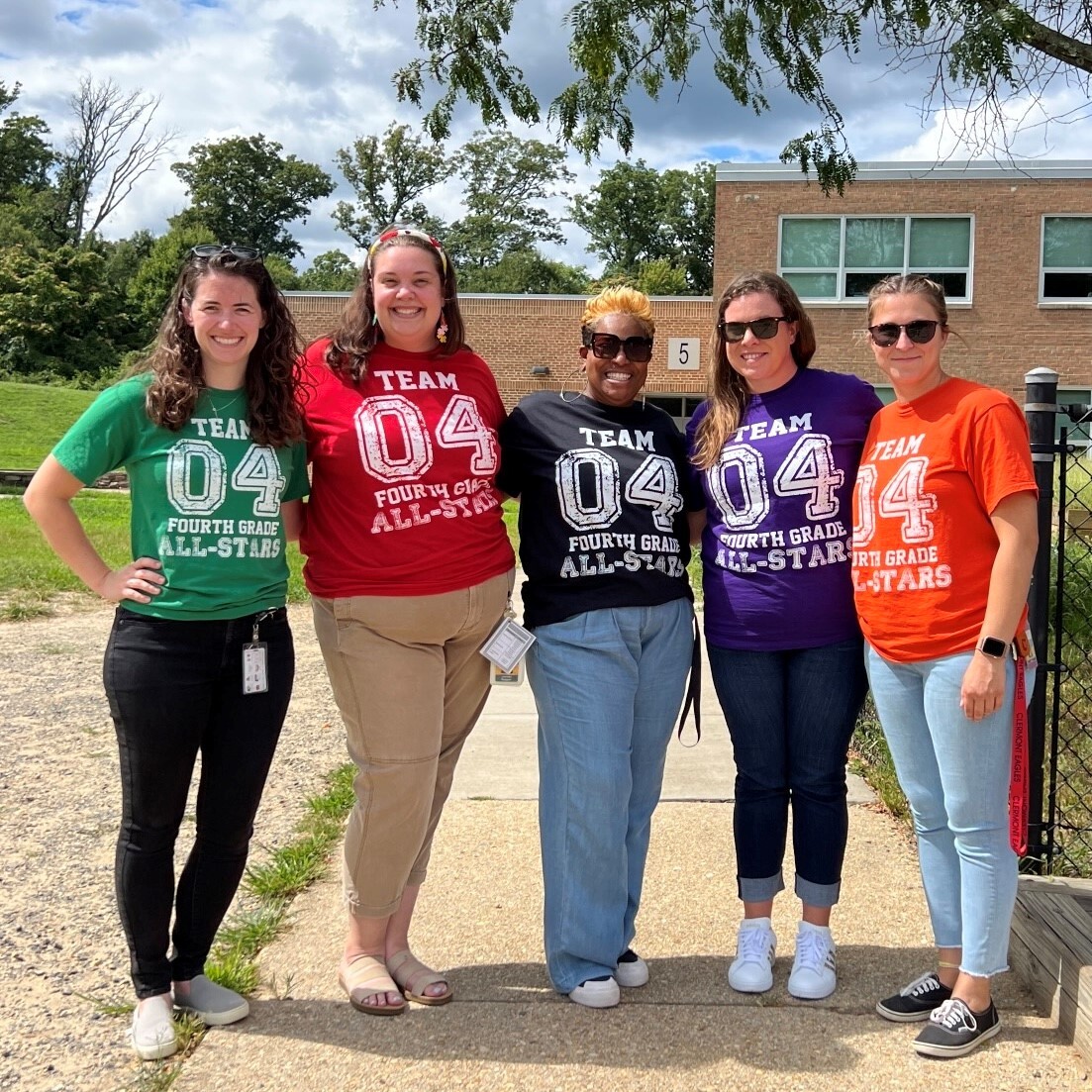 The fourth grade staff of Clermont pose in matching shirts outside. 