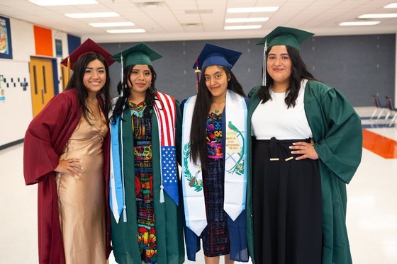four students smiling in their cap and gown