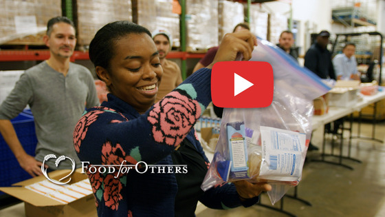 Food for Others leader sharing "how to pack food" with care to volunteers.  Food for Others supports FCPS.
