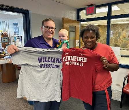 two people holding up college t shirts