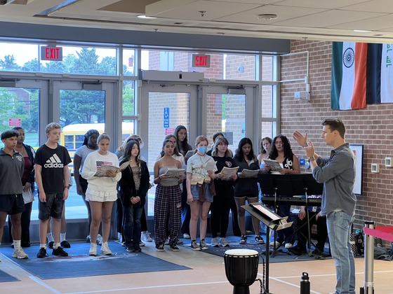 Students singing in front of windows