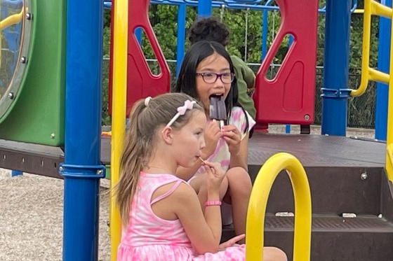 Students enjoying popsicles on the playground equipment