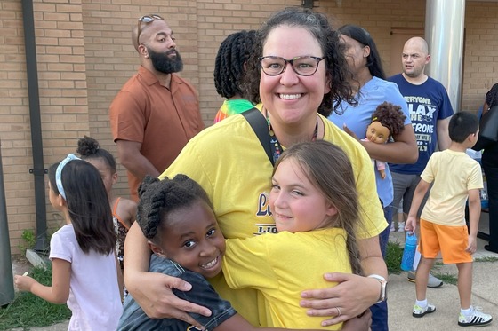 A teacher hugs two students at the back-to-school popsicle event