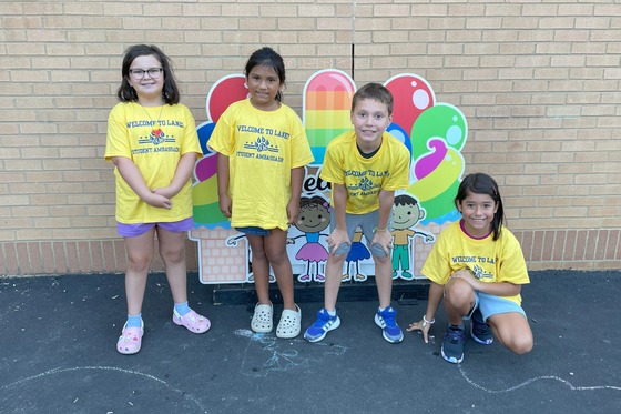 Students in front of a popsicle welcome sign