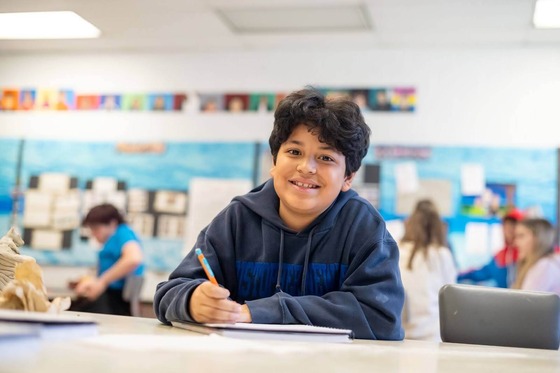 student smiles as he writes