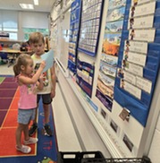 students reading a paper by the whiteboard