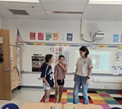 students and teacher standing in front of room