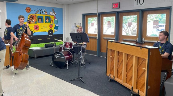 Music teachers playing instruments in the hallway to greet families