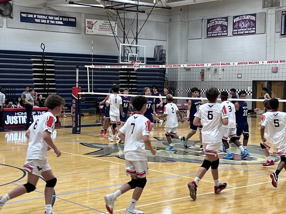 boy volleyball team by the net shaking hands with the other team