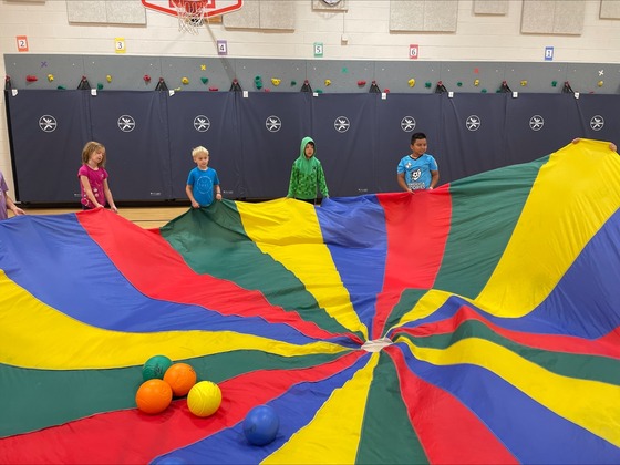 Students holding a parachute with a ball on it in physical education 