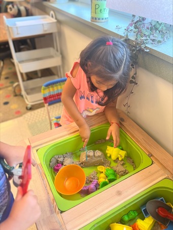 A young student explores the sandbox during explore time 