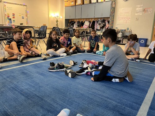 Students put their shoe in the middle of a circle and try to figure out whose it is 