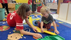 Preschool teacher on carpet with student