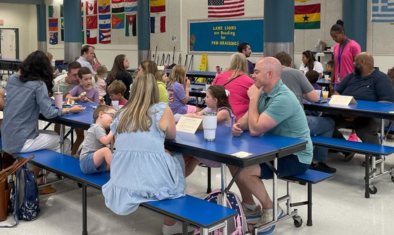 Kindergarten families enjoying breakfast and conversation in the cafeteria at the Kindergarten Breakfast Bites event