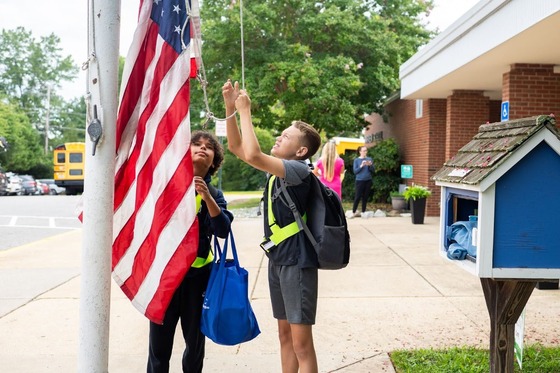 student raising a flag on the flag pole