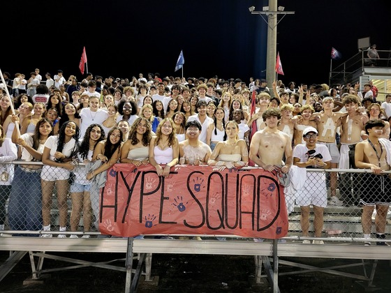 Students on stadium bleachers with a sign that says Hype Squad