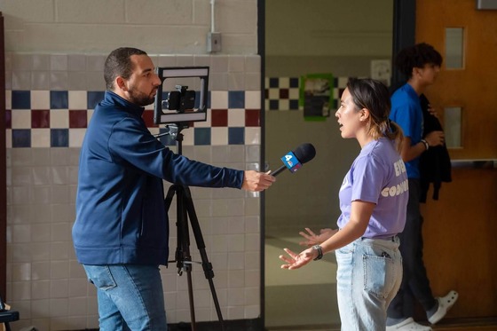 person speaking into a microphone that is being held by another person