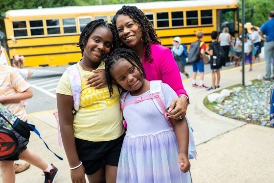 Mother standing in front of school with their two daughters