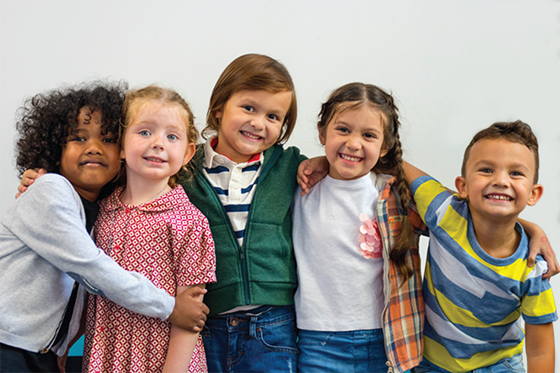 A group of elementary students standing together with arms around one another