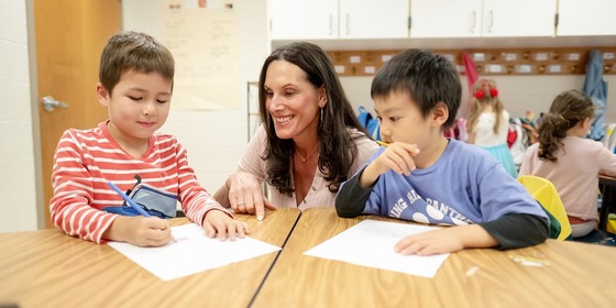 teacher sitting at a table working with students