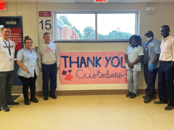 Morning Shift custodians stand next to their Thank You banner