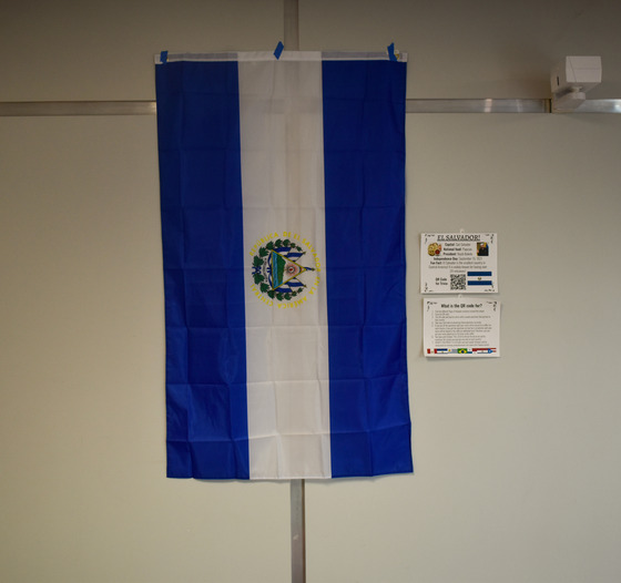 El Salvador flag with QR code information as example of all of the different flags that are hanging up throughout the school