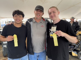 2 students holding 5th place ribbons with a teacher standing between them