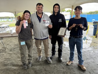 4 people standing holding winning ribbons