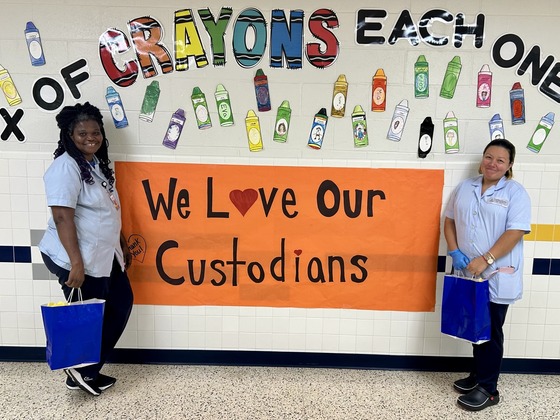 A photo of two of our wonderful custodians with a banner that says "We love our custodians".