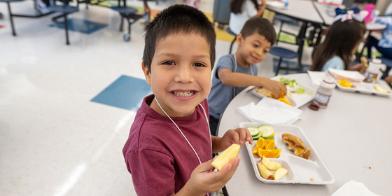 photo of students smiling while eating lunch 