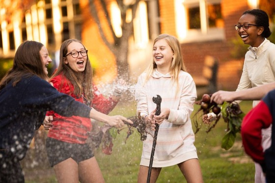 students playing with a hose while gardening