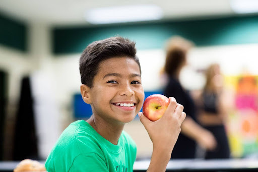 student smiling while eating an apple