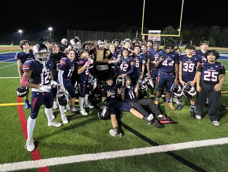 Football players standing on the field holding a trophy