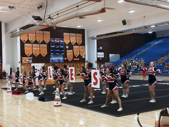 cheerleaders cheering holding letter signs that spell eagles