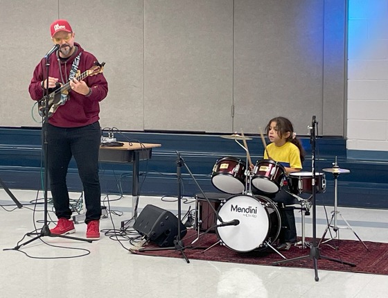 Father playing guitar and daughter playing drums perform Latin music