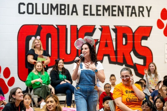 Teacher speaks into a microphone at an assembly