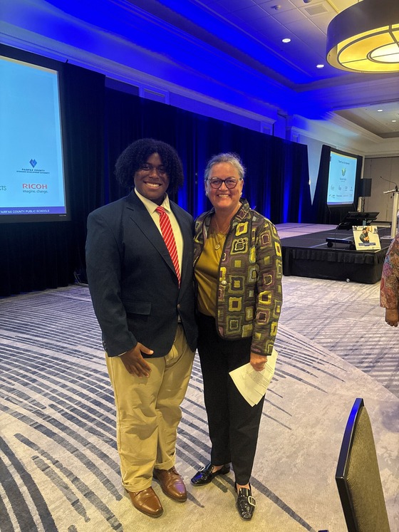 a student and an adult standing in a convention room