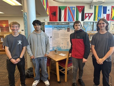 4 students standing on either side of a poster board that says water purification project