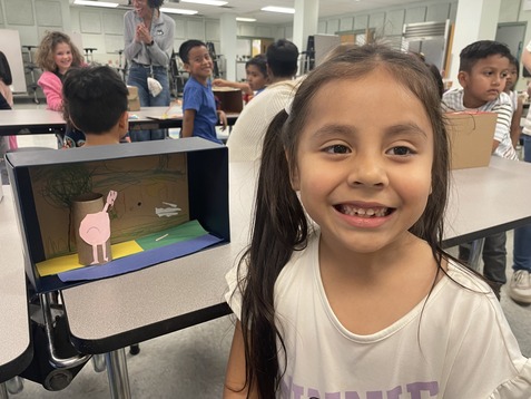 Kindergarten student smiles with project 